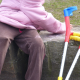 Bambina seduta su un muretto con accanto stampelle colorate