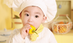Bambino vestito da cuoco che mangia un peperone